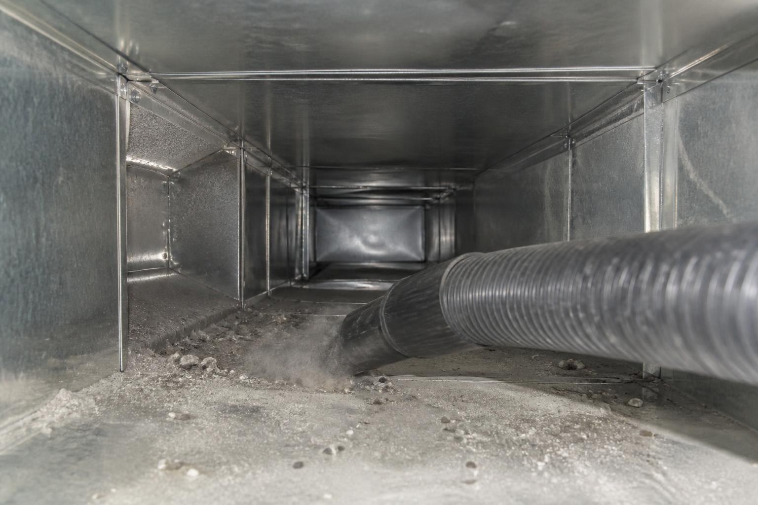 Vacuum hose removing dust and debris from inside a supply duct trunk line
