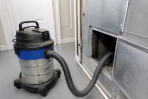 Duct cleaning vacuum hose connected to a residential ductwork access panel